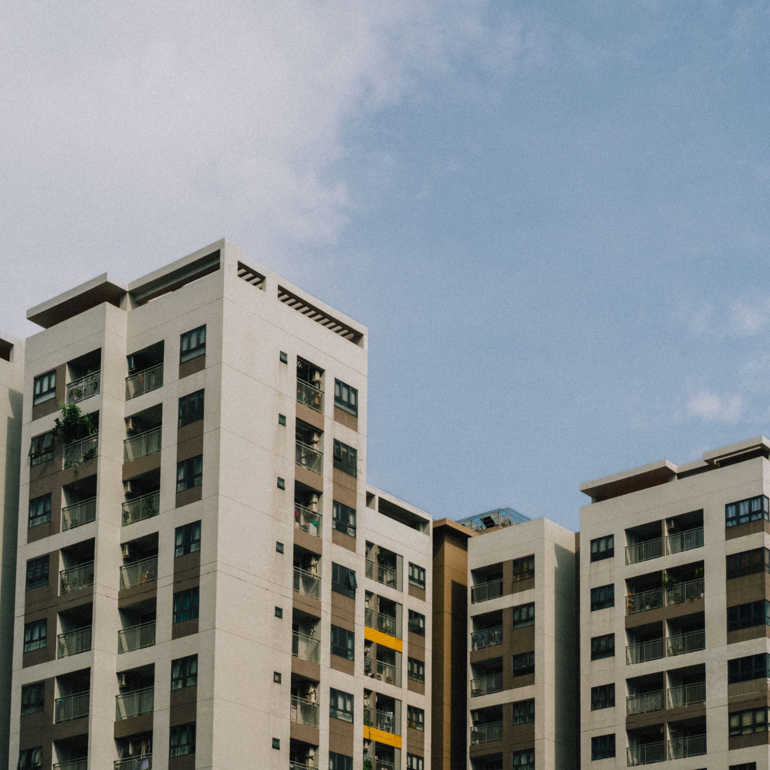 High-rise apartment buildings with balconies under a bright blue sky, showcasing urban architecture.